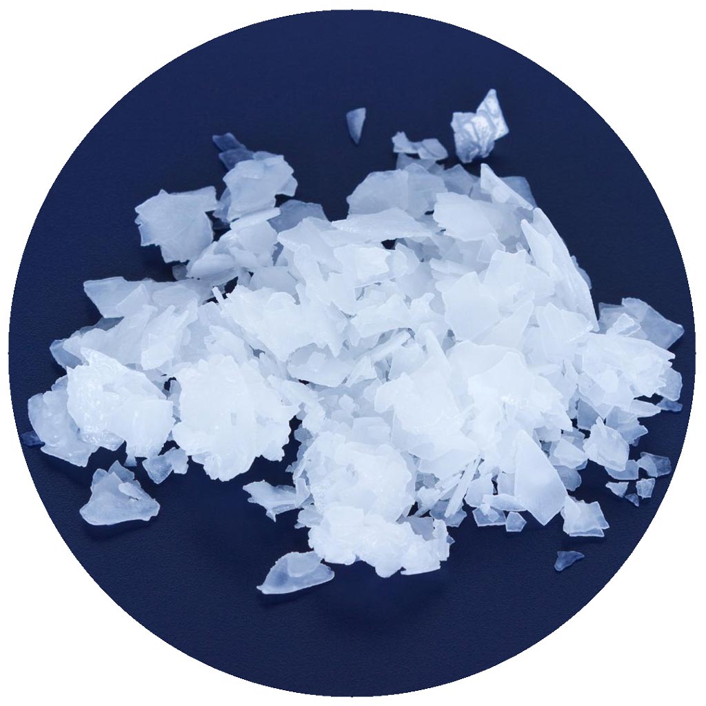 A pile of white, translucent flakes scattered on a dark blue surface. The flakes have a crystalline, jagged appearance and are grouped in the center of a circular frame.