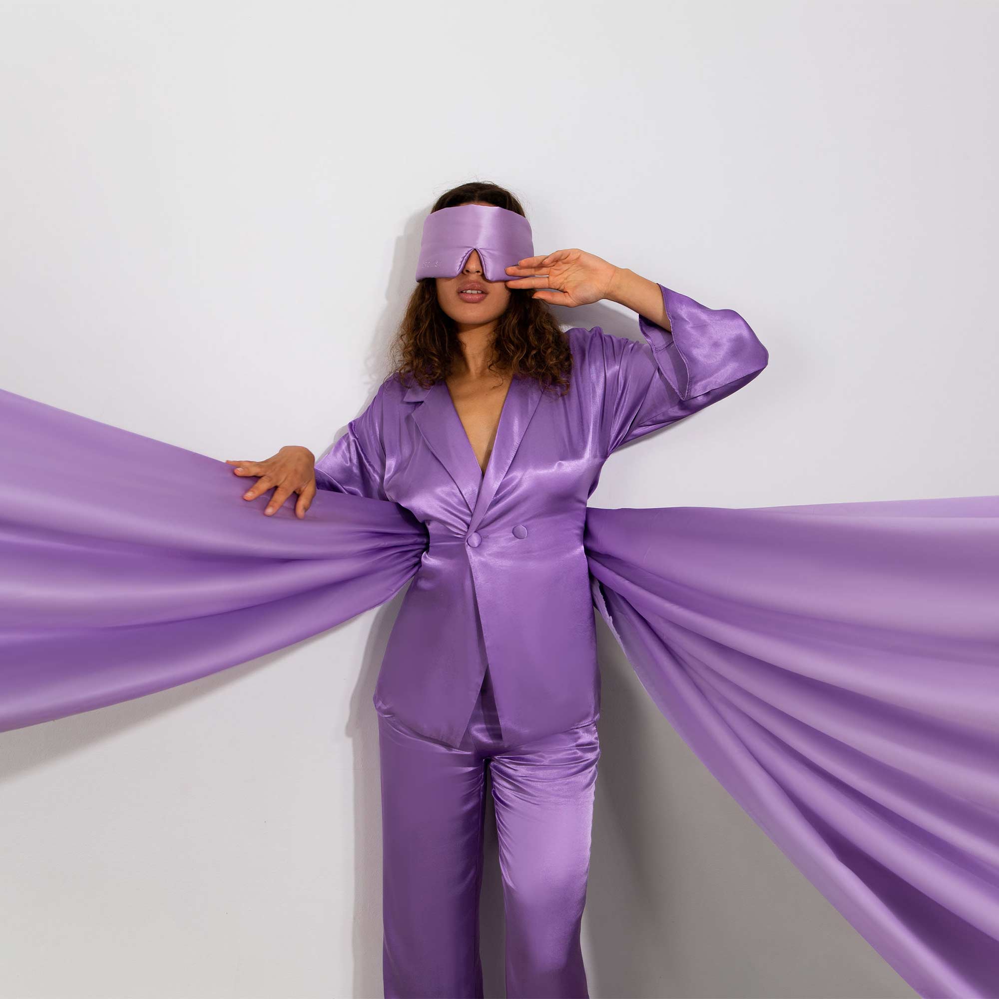 Model with Lavender coloured Drowsy sleep mask covering eyes with a purple silk backdrop