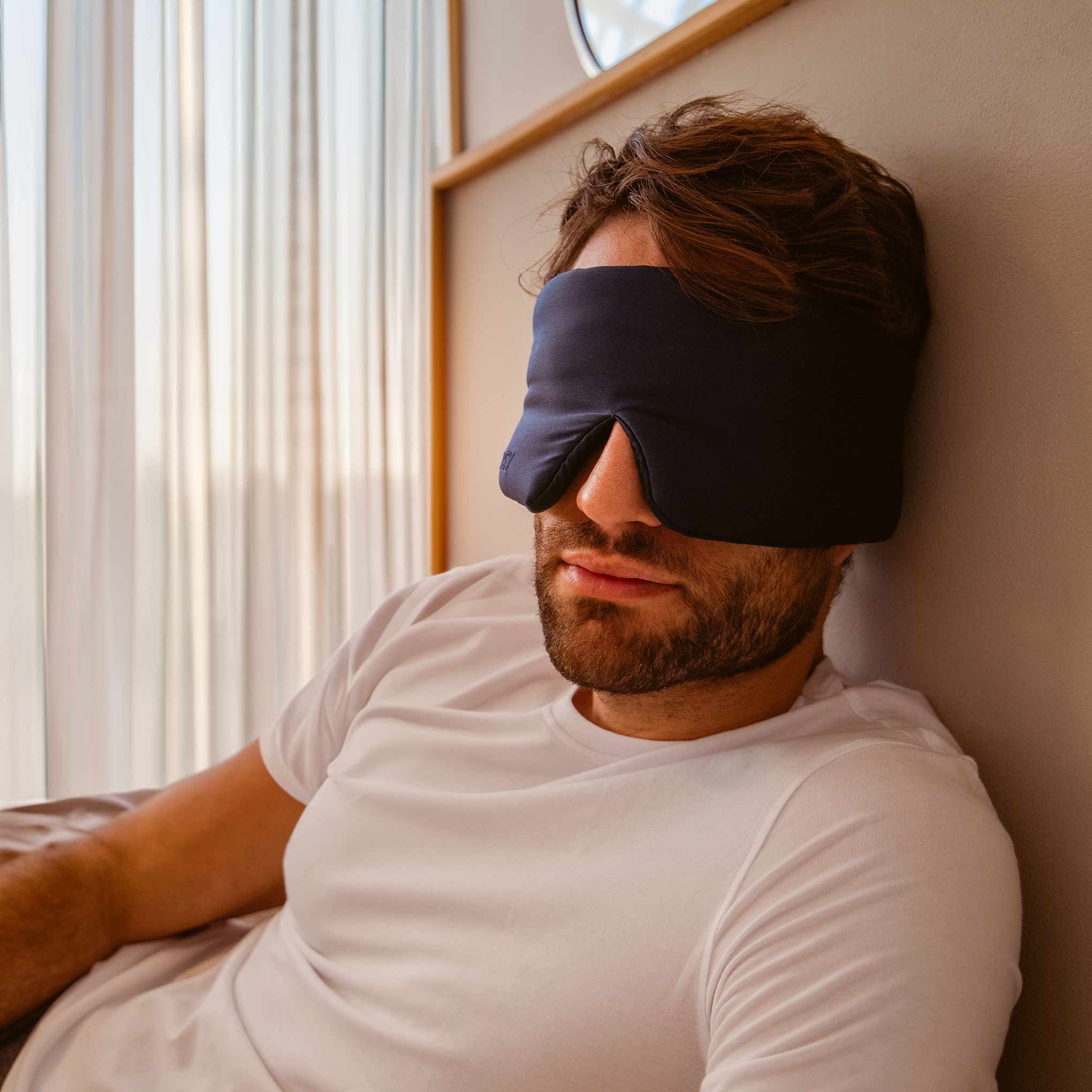 A man wearing the drowsysleepco 2-Pack Sleep Masks in Paris Love Story and Midnight Blue.