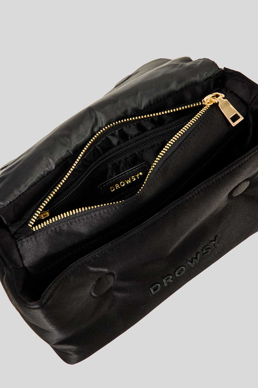A black Sleepover bundle - Black Jade bag by Drowsy is open, showing a gold zipper and an interior pocket with the Drowsy logo, set against a light gray background.
