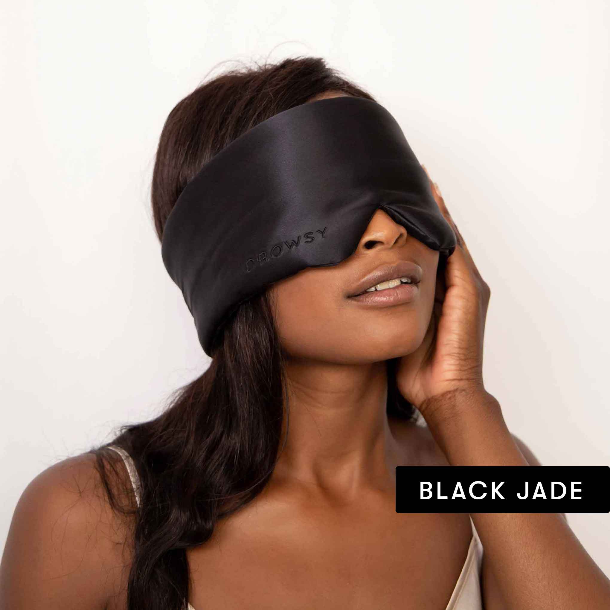 A woman with long dark hair wears a large luxury silk mask from Drowsy’s Besties Pack and gently touches her face, embodying beauty sleep. The words BLACK JADE appear in a black rectangle at the bottom right.
