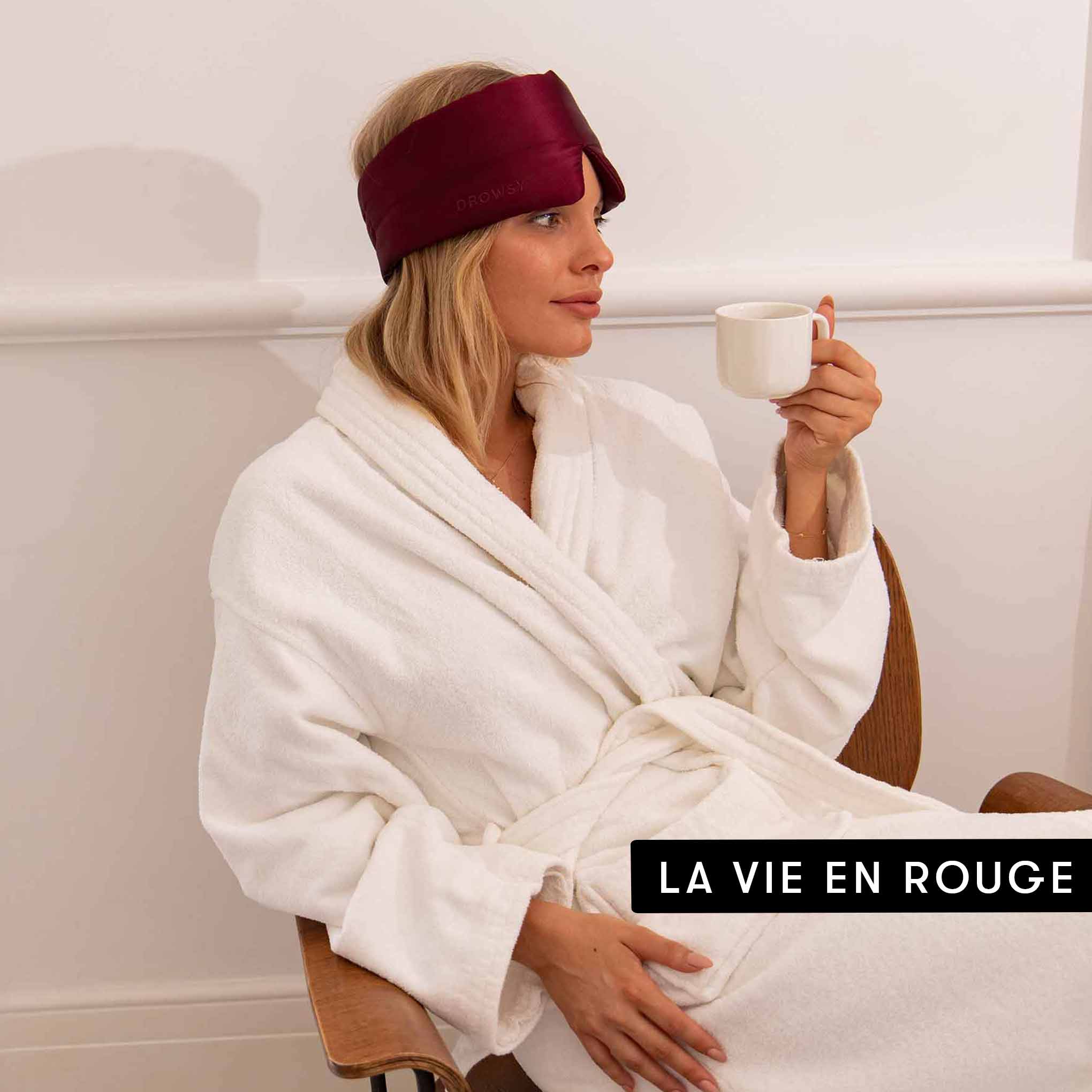 A woman in a white bathrobe relaxes with a mug, wearing the Drowsy Lovers Pack burgundy silk mask. The text “LA VIE EN ROUGE” appears in the bottom right corner.