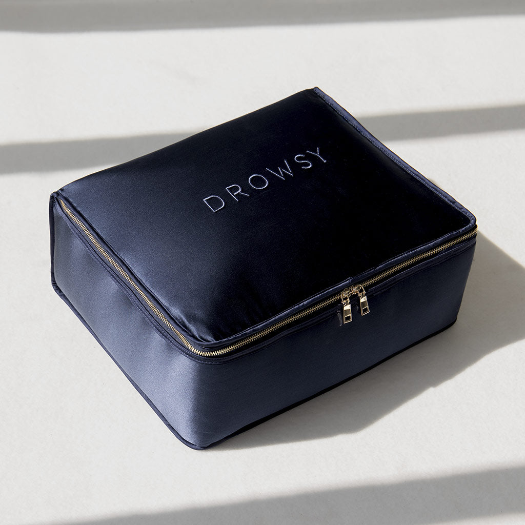 A rectangular, midnight blue silk weighted blanket by us.drowsysleepco evokes deep relaxation as it rests on a light surface with soft shadows.