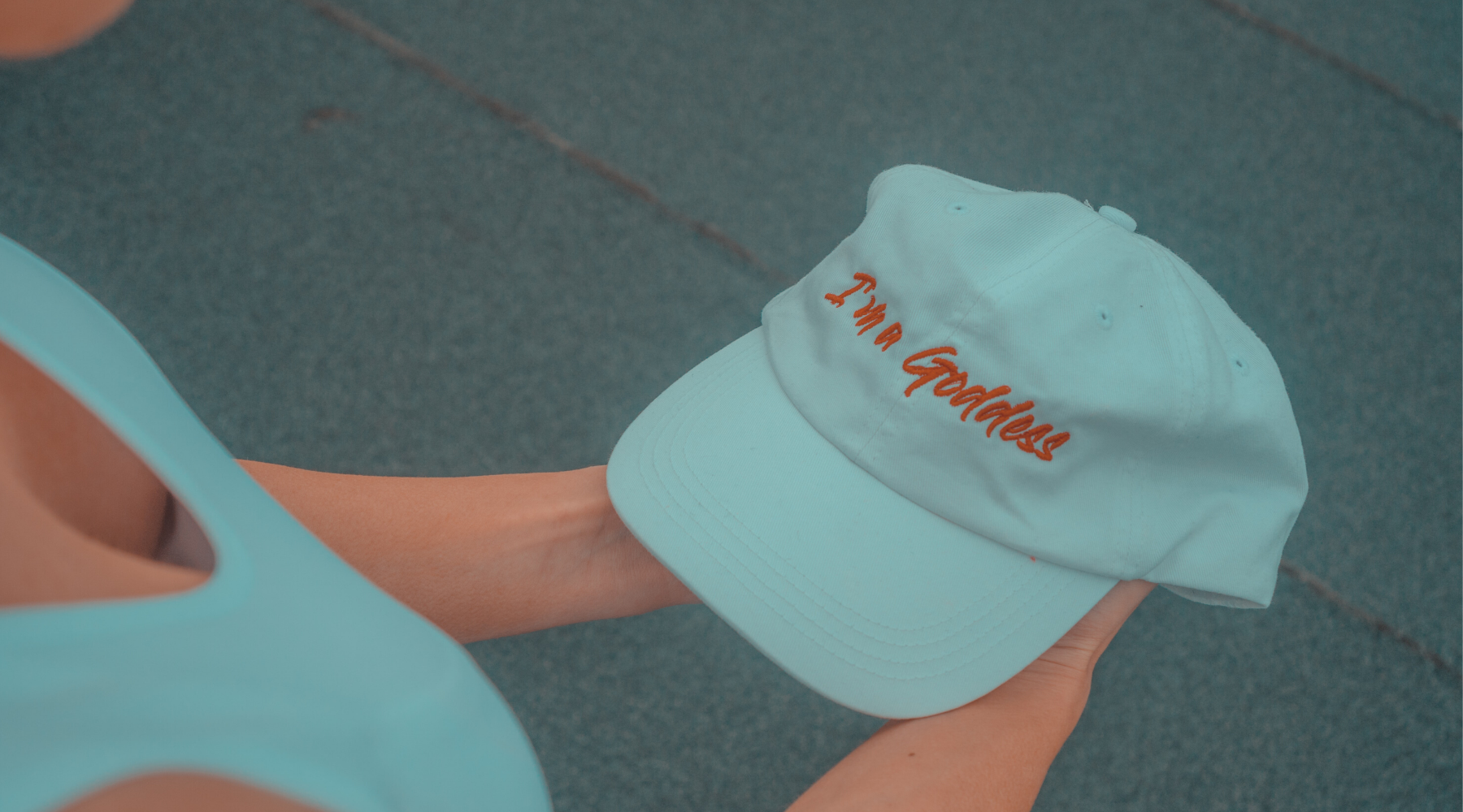 Girl holding a cap that says i'm a goddess