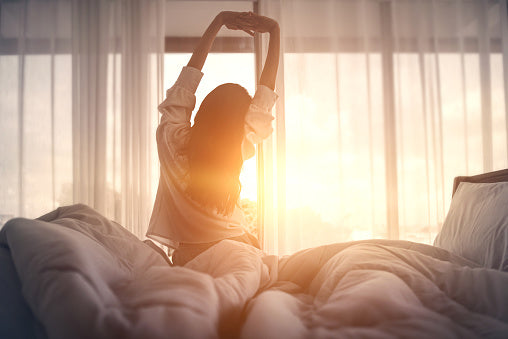 Girl looking out of the window stretching in the morning 