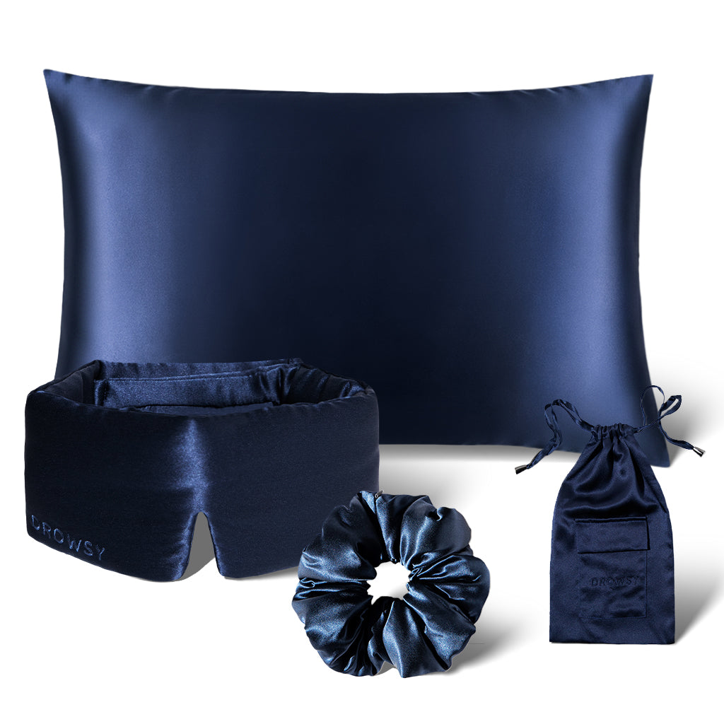 Explore the Sensual Sleep Bundle - Midnight Blue by drowsysleepco: a dark blue satin set featuring a pillowcase, sleep mask, scrunchie, and drawstring pouch, all elegantly shown against a white backdrop.