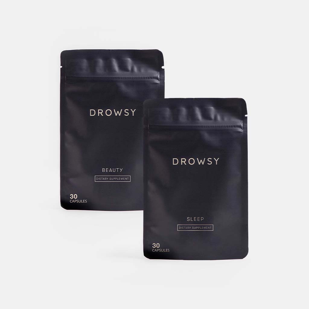Two black resealable pouches from drowsysleepco’s Beauty Sleep Clinic Subscription stand against a plain white background. Labeled Beauty and Sleep, each pouch contains 30 dietary supplement capsules.