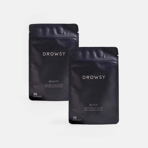 Two black resealable pouches from drowsysleepco’s Beauty Sleep Clinic Subscription stand against a plain white background. Labeled Beauty and Sleep, each pouch contains 30 dietary supplement capsules.
