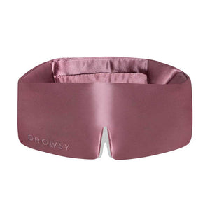 The Damask Rose eye mask by us.drowsysleepco is wide, silky pink with Drowsy embossed on the front, a central notch, and a soft padded blackout interior for enhanced comfort and rest.