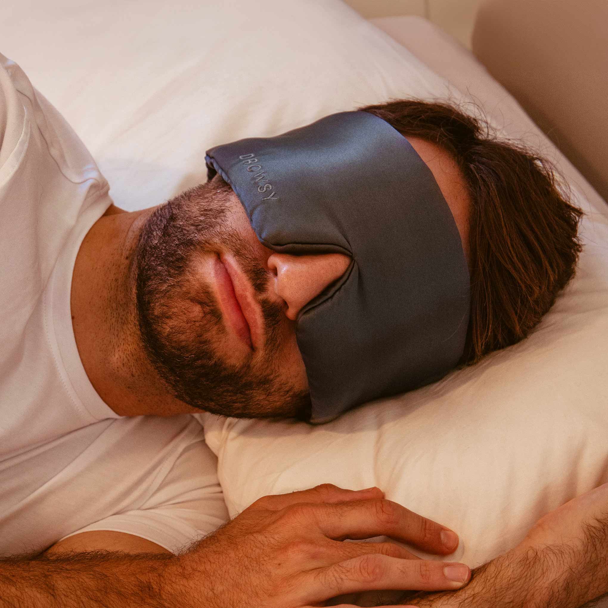 Male model sleeping in bed with grey Drowsy silk sleep mask covering his eyes