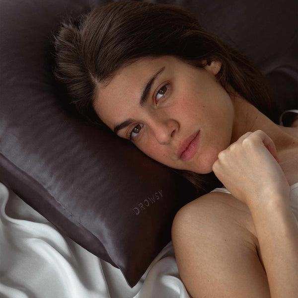 Model lying on a charcoal coloured Drowsy silk pillowcase