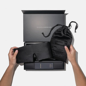 Two hands hold the Black Jade - Deep Sleep Collection by us.drowsysleepco: a luxury silk sleep mask and black carry pouch above a gift box with sleep products, including deep sleep pillow spray. Inside the lid: YOU DESERVE GLORIOUS SLEEP.