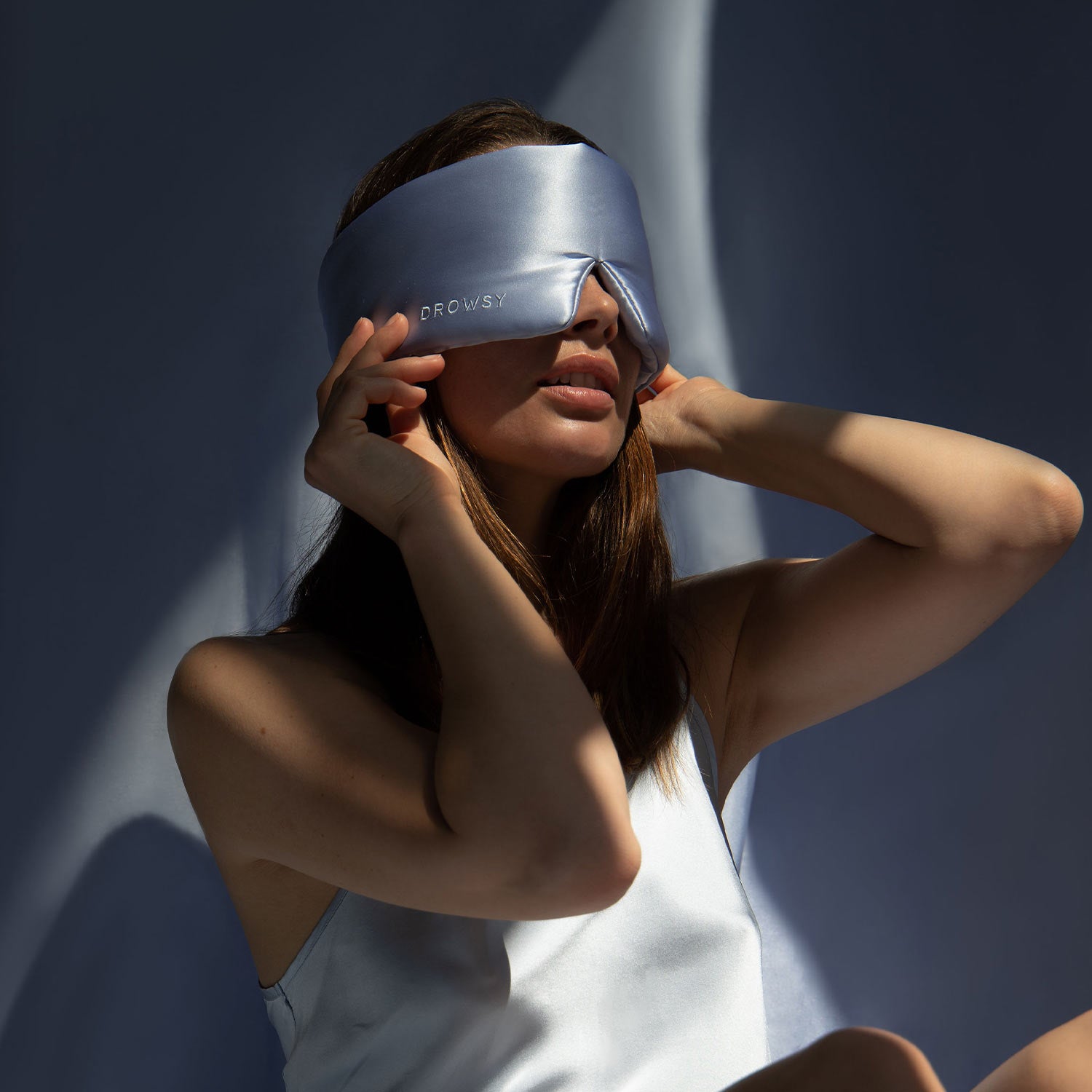 Model with baby blue coloured Drowsy silk sleep mask blocking out light from her eyes